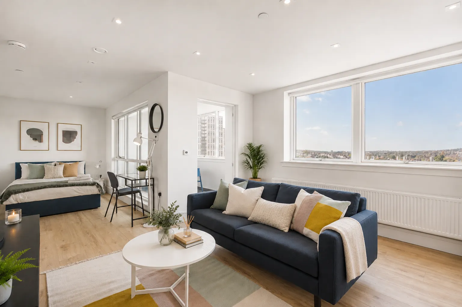 Living area with a navy sofa beside floor-to-ceiling windows, in a one-bedroom flat at Vonder Wembley