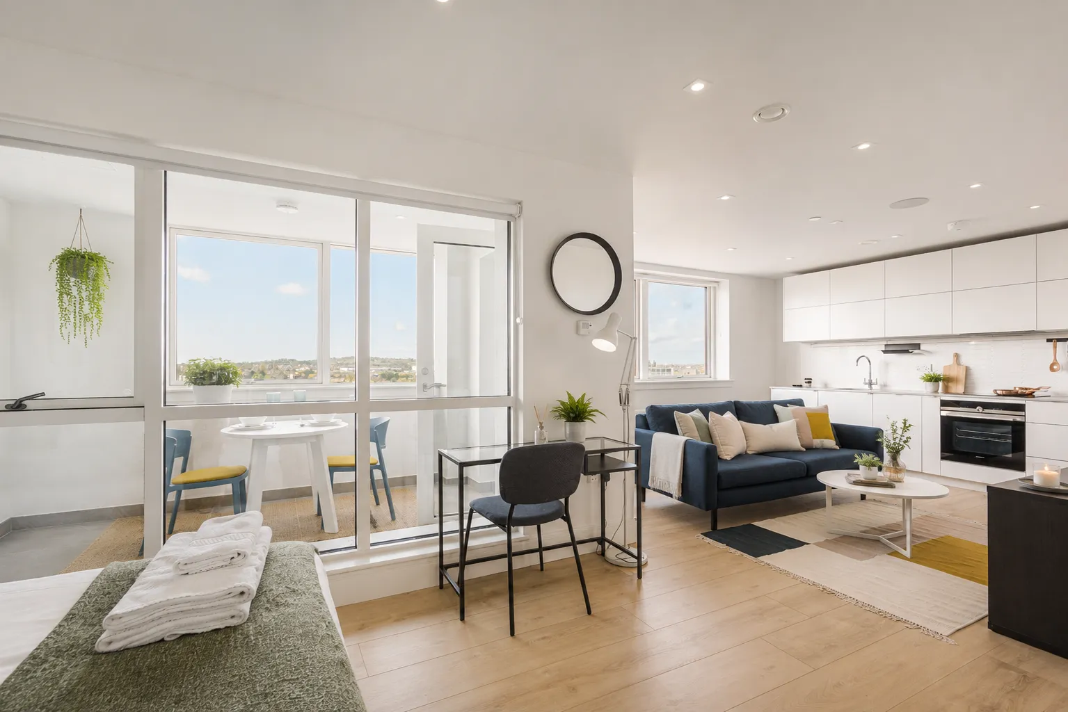 Living and dining area with the kitchen beyond and views over Wembley, in a one-bedroom flat at Vonder Wembley