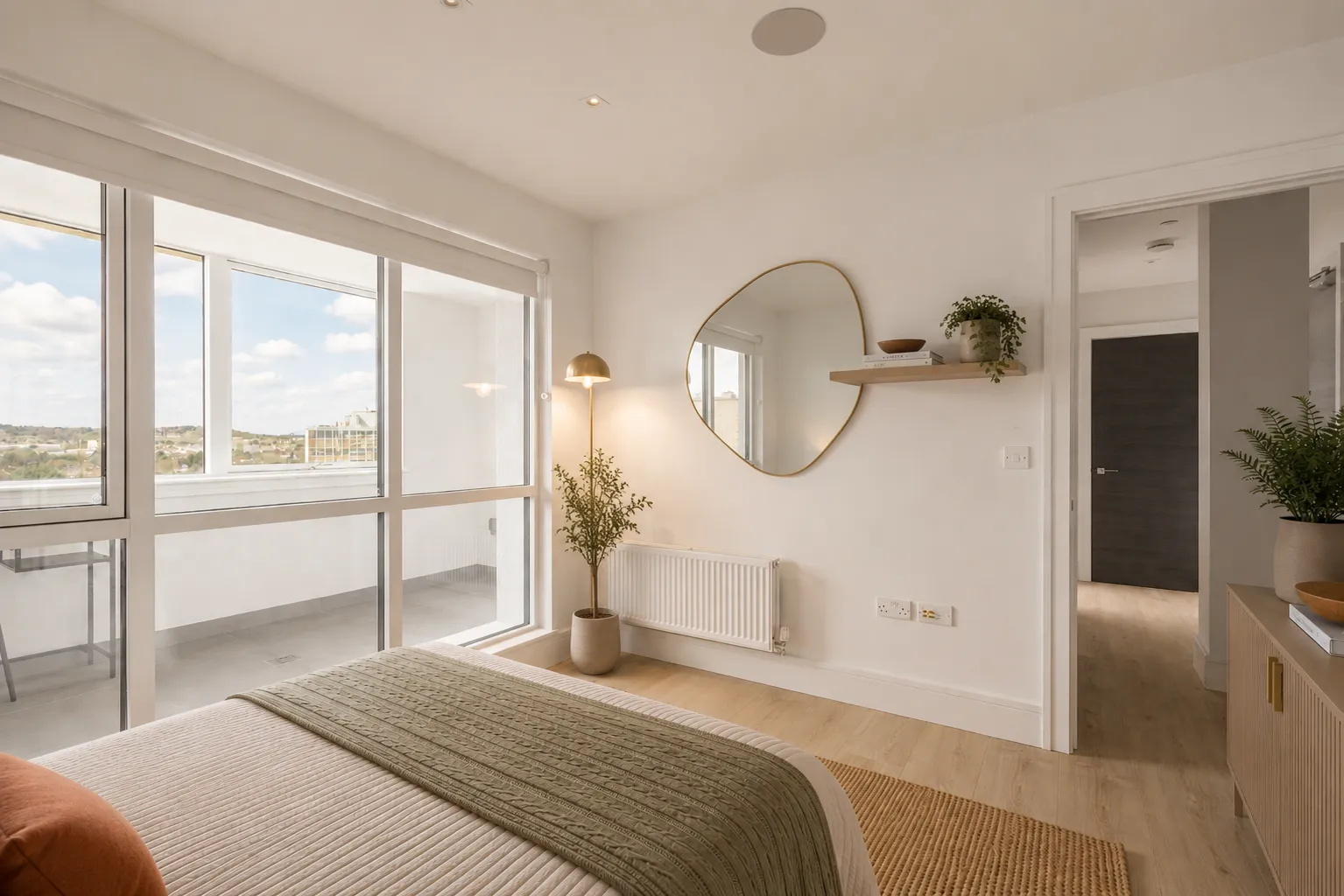 Bedroom with floor-to-ceiling windows and a round mirror, looking through to the hallway, at Vonder Wembley
