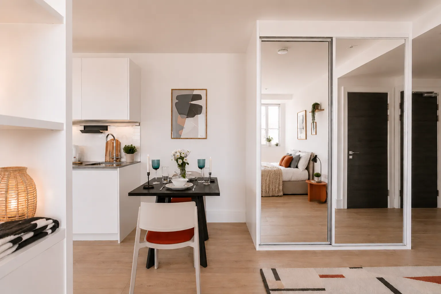 Dining area beside mirrored wardrobes, looking through to the bedroom, in a one-bedroom flat at Vonder Wembley