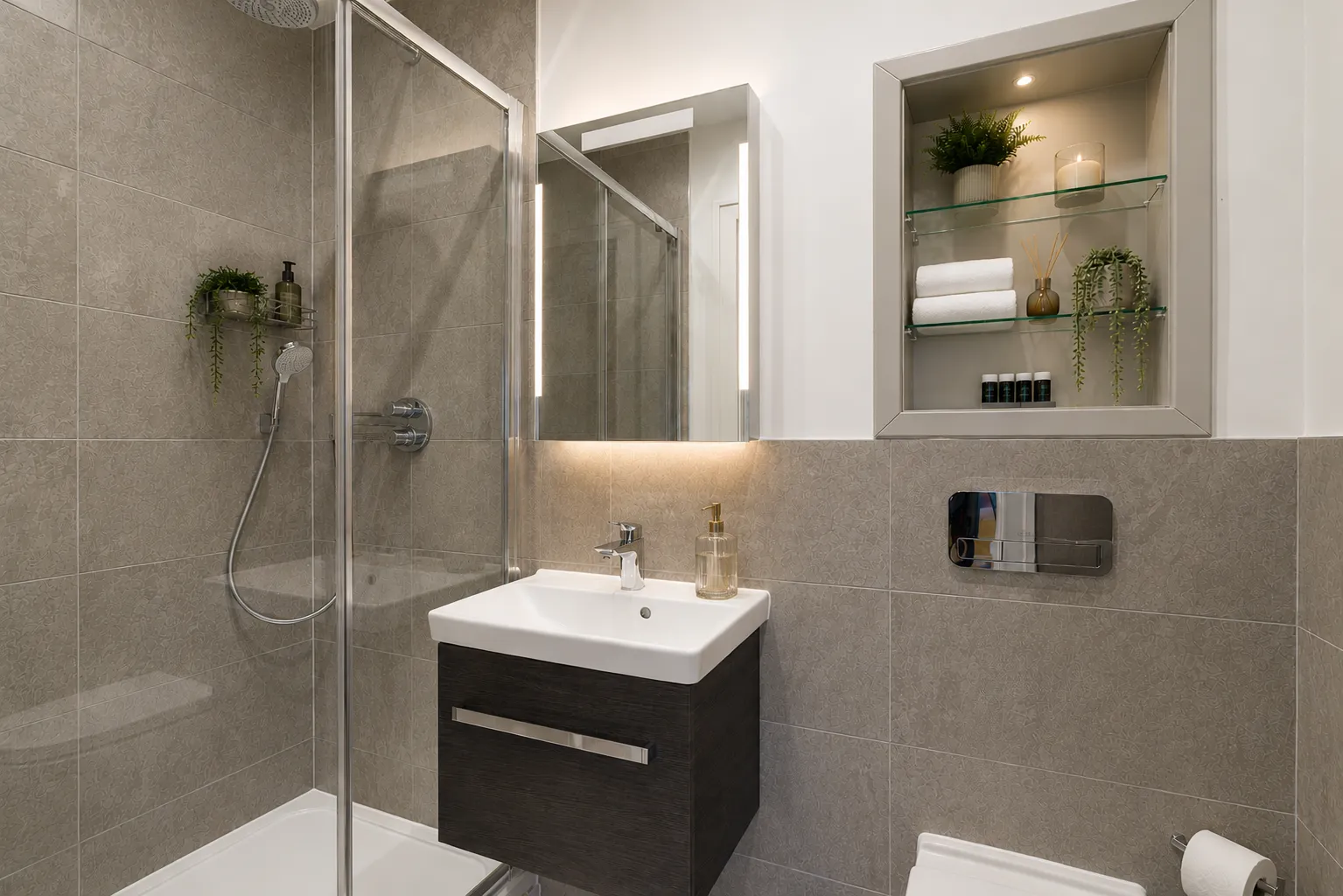 Tiled bathroom with a walk-in shower and wall-hung basin, in a one-bedroom flat at Vonder Wembley