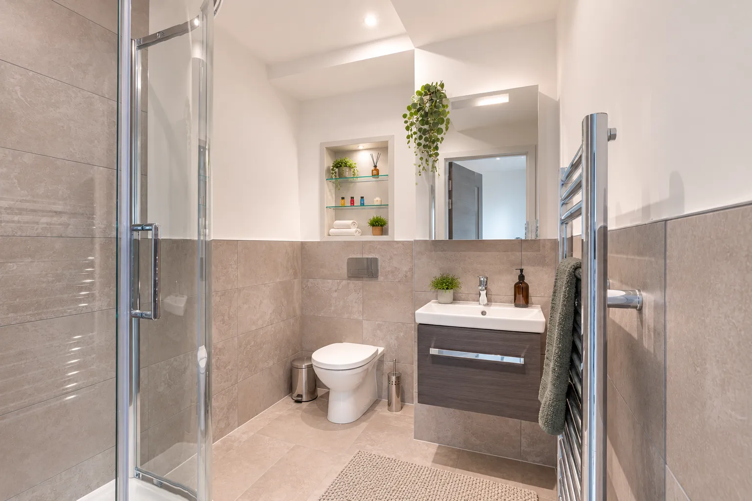 Tiled bathroom with a walk-in shower, basin and heated towel rail, in a one-bedroom flat at Vonder Wembley