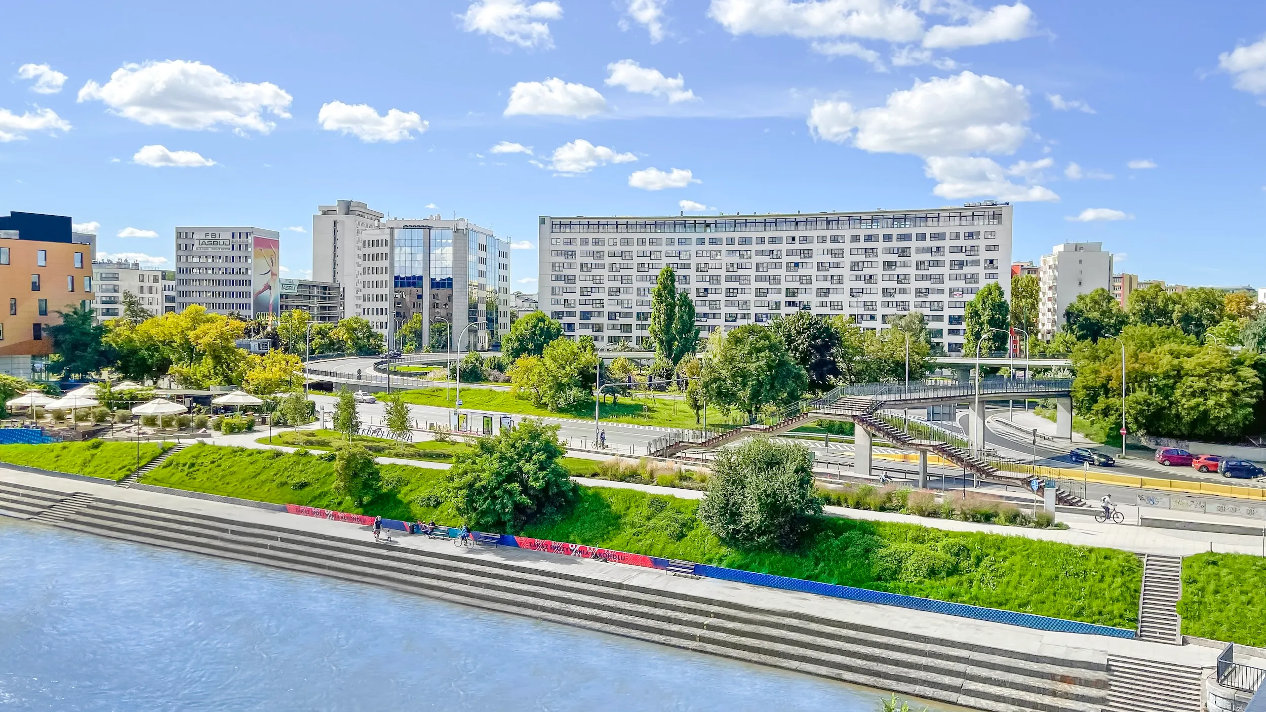 Vonder Upriver seen across the river, with landscaped riverside gardens in front of the buildings