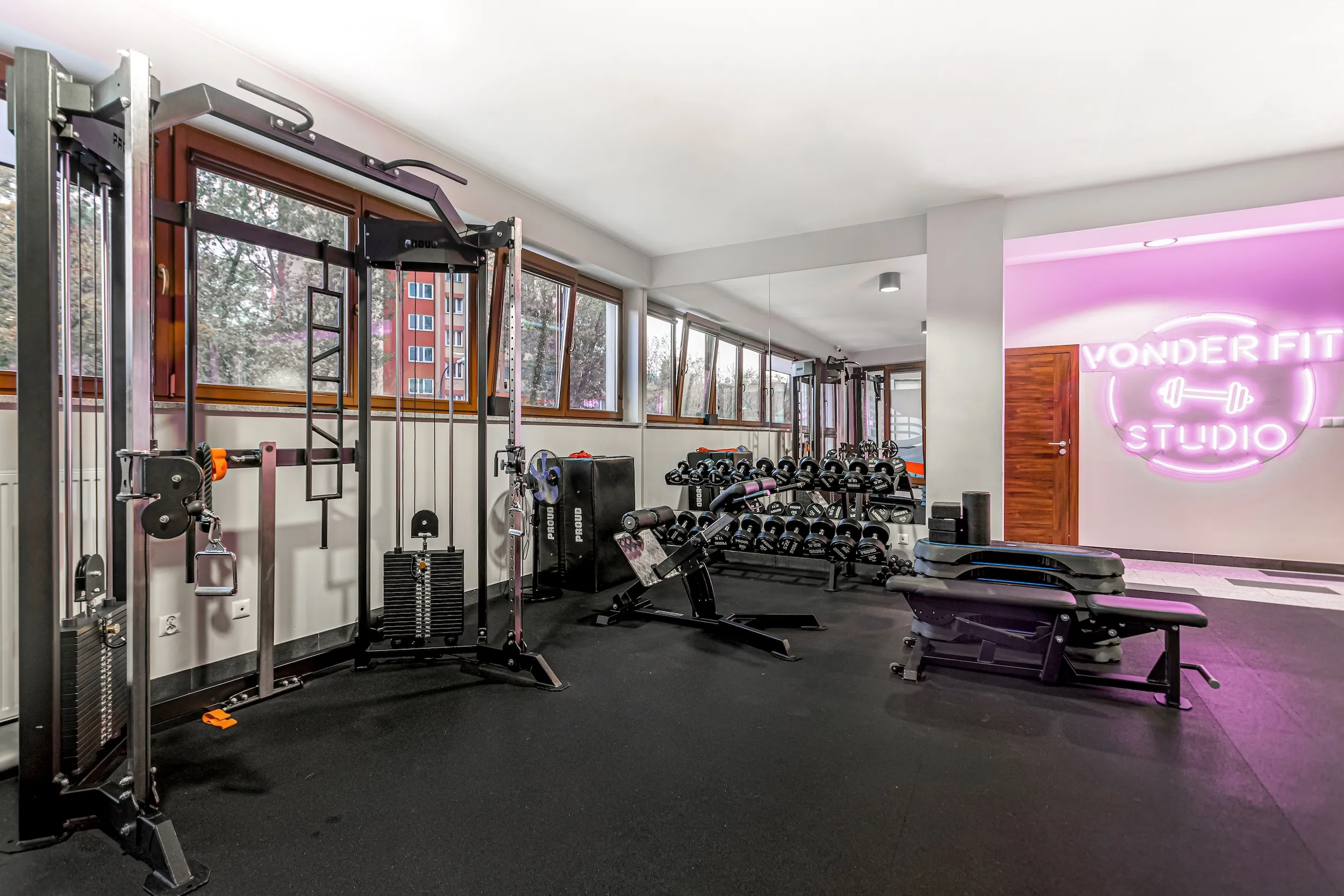 Vonder Upriver gym with a cable machine, dumbbells and a pink neon studio sign