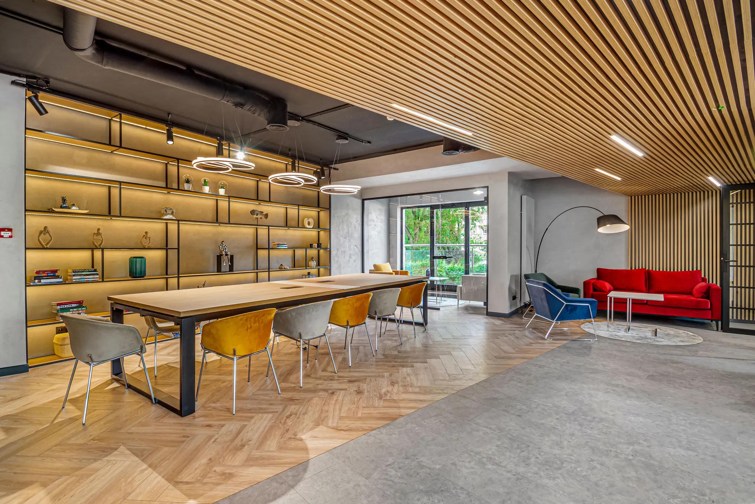 Shared lounge at Vonder Upriver with a long dining table, shelving and a red sofa