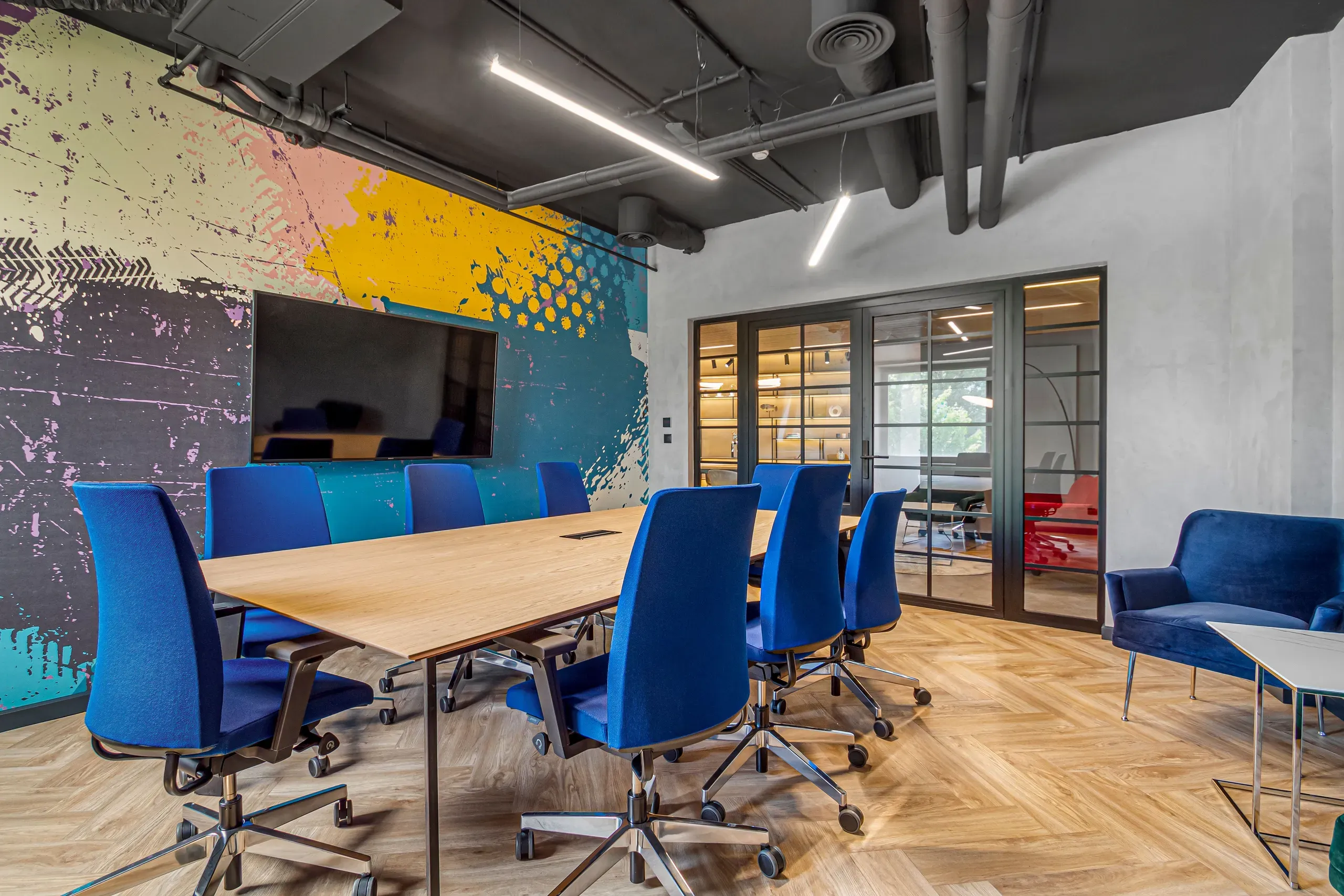 Meeting room at Vonder Upriver with blue office chairs, a screen and a graffiti-style wall