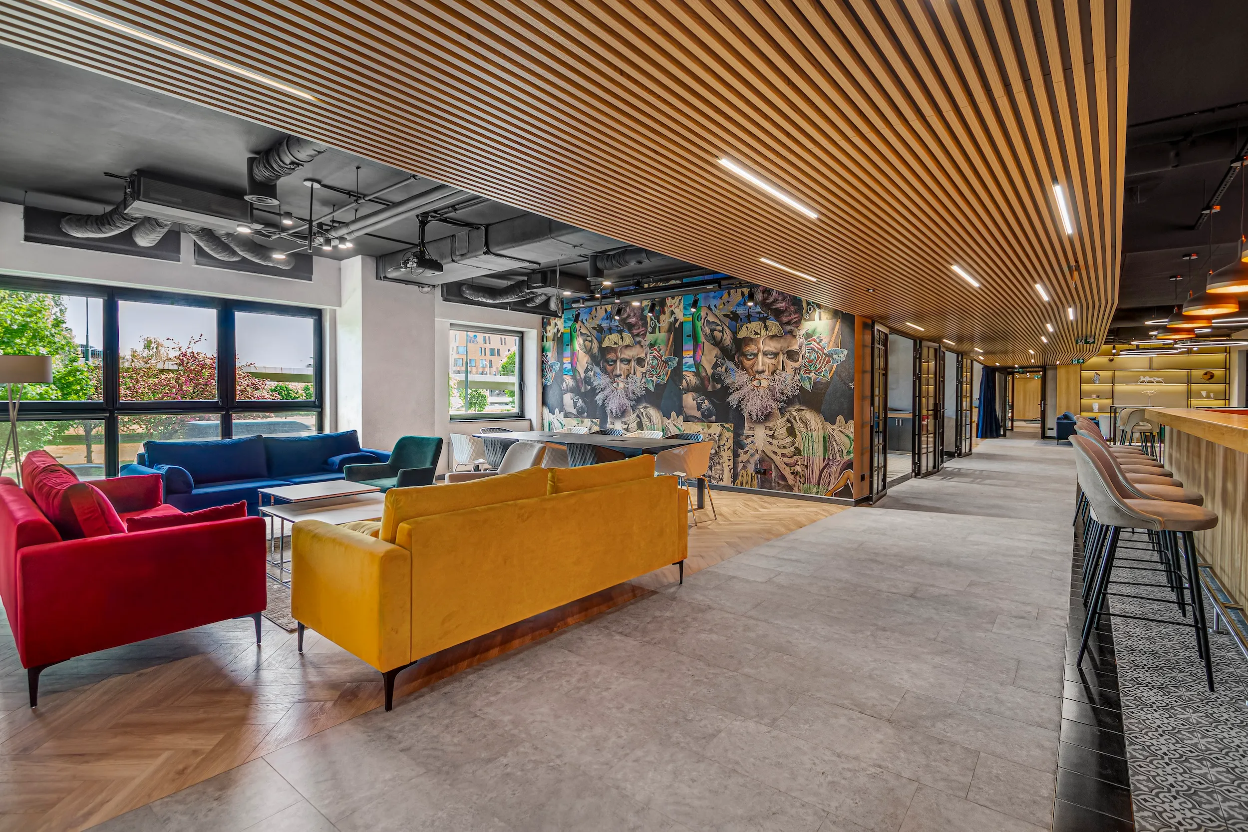 Residents' lounge at Vonder Upriver with red and yellow sofas under a slatted wood ceiling
