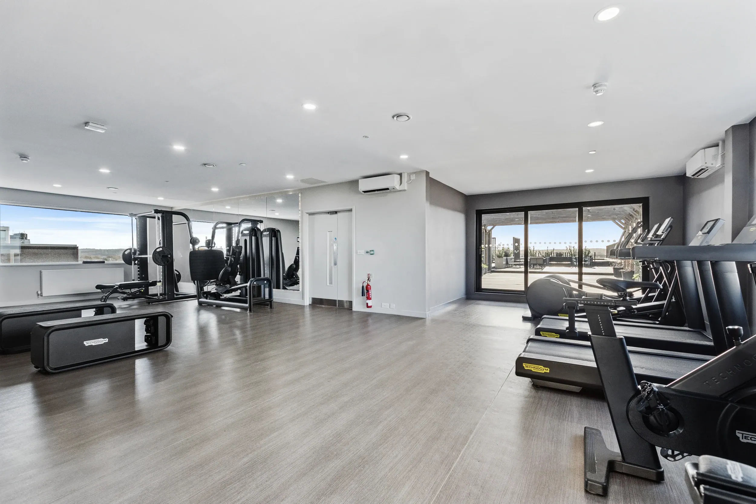 Residents' gym at Vonder Crawley, with cardio machines and doors onto the terrace