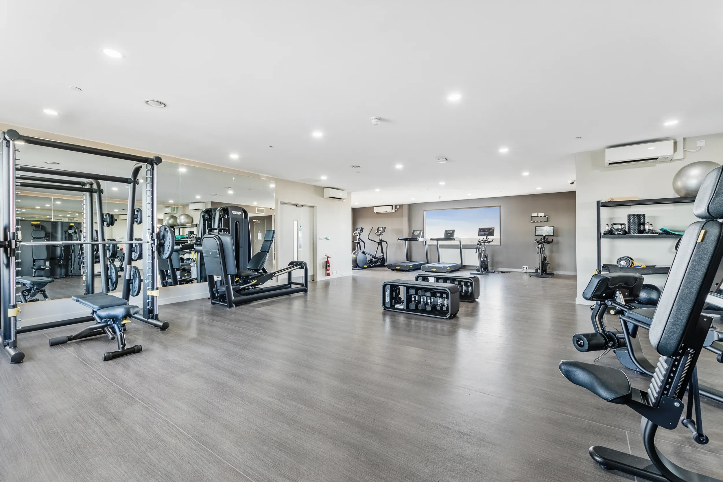 Residents' gym at Vonder Crawley, with a squat rack, dumbbells and mirrored walls