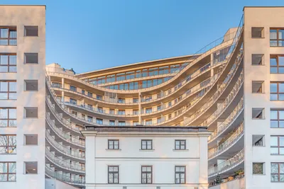 Curved facade of Vonder Upriver with rows of balconies against a blue sky