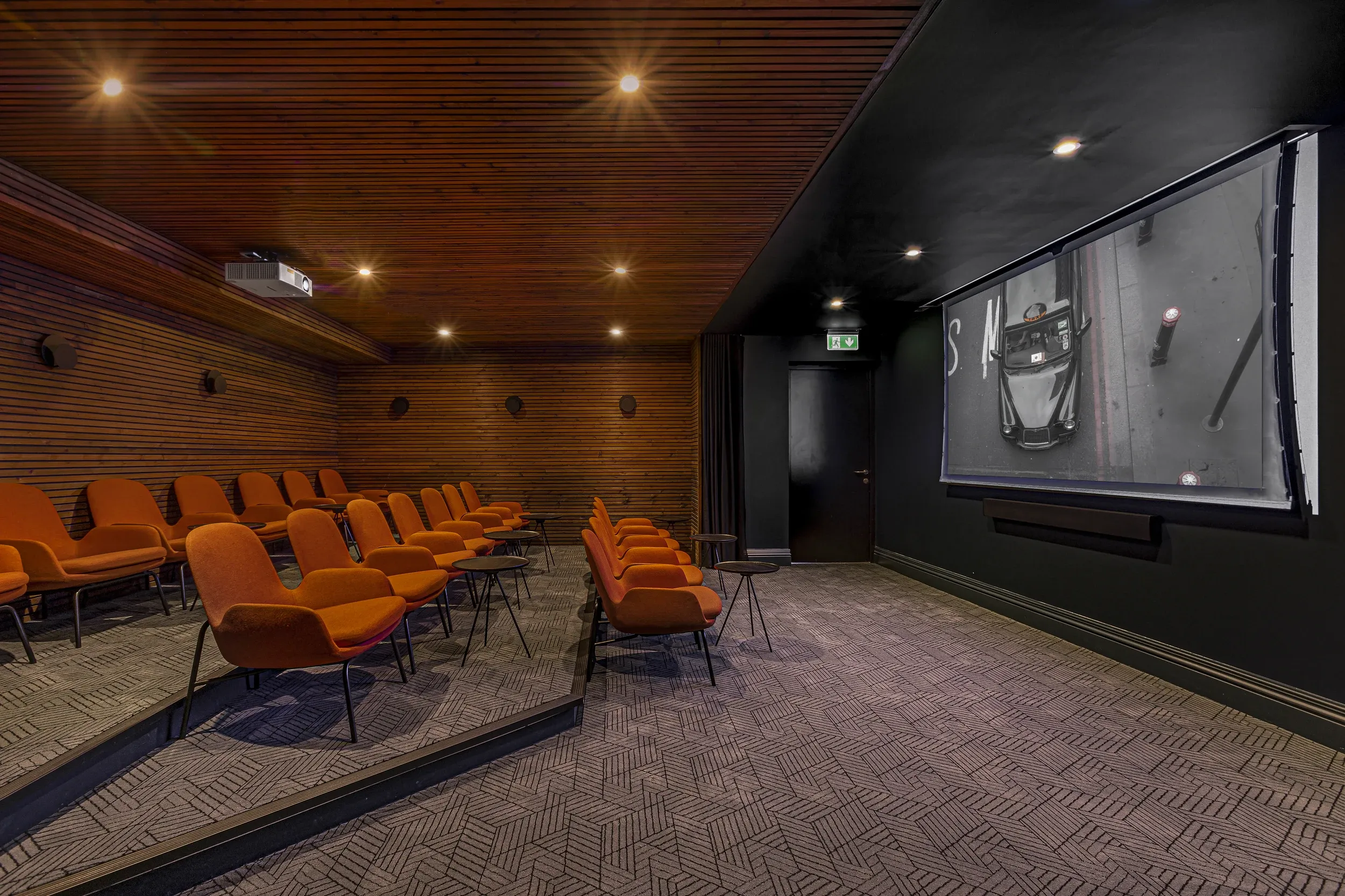 Residents' cinema room at Vonder Wembley, with tiered orange seating facing a projection screen