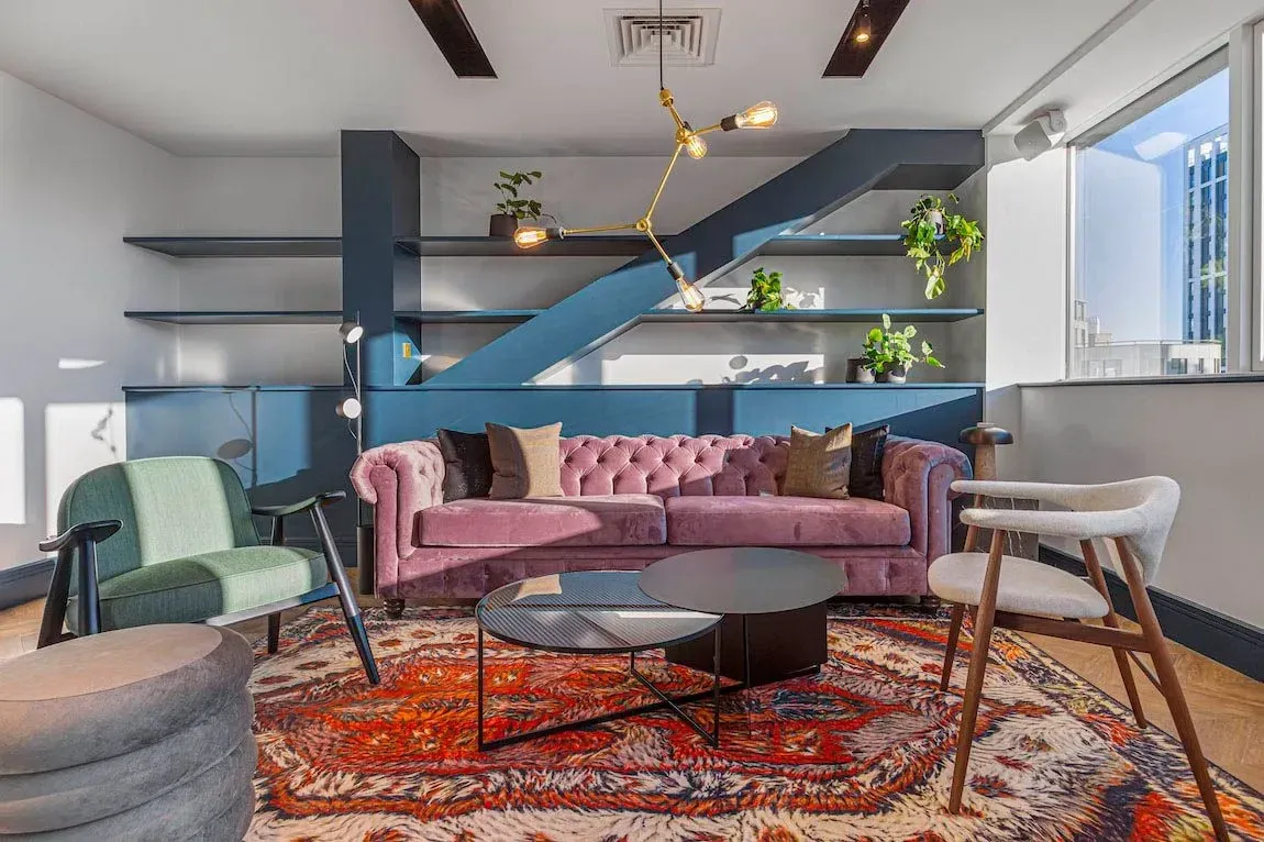 Snug seating area at Vonder Wembley with a pink sofa, patterned rug and slatted screen