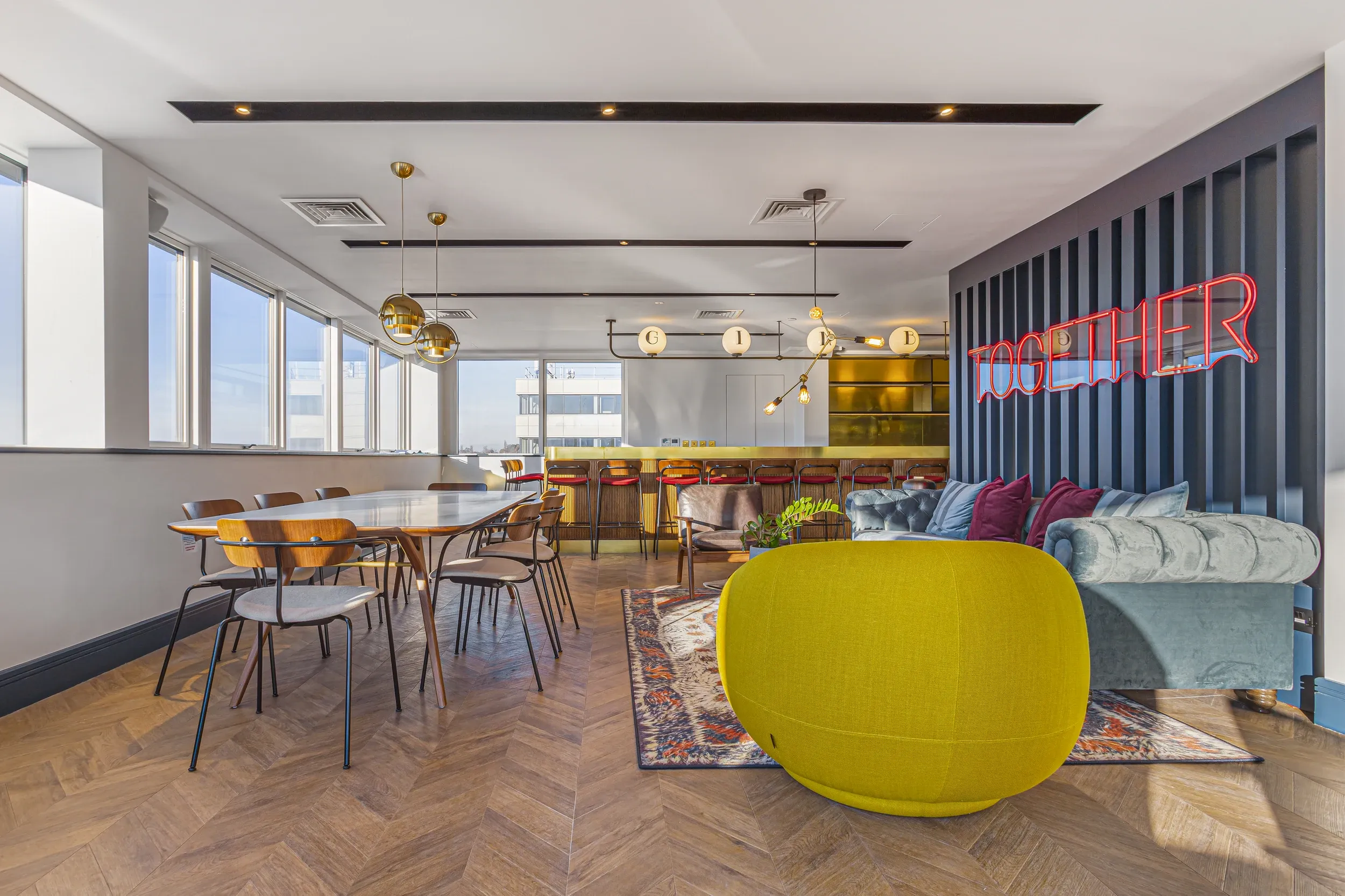 Members' lounge at Vonder Wembley, with a long communal table, bar and herringbone floor