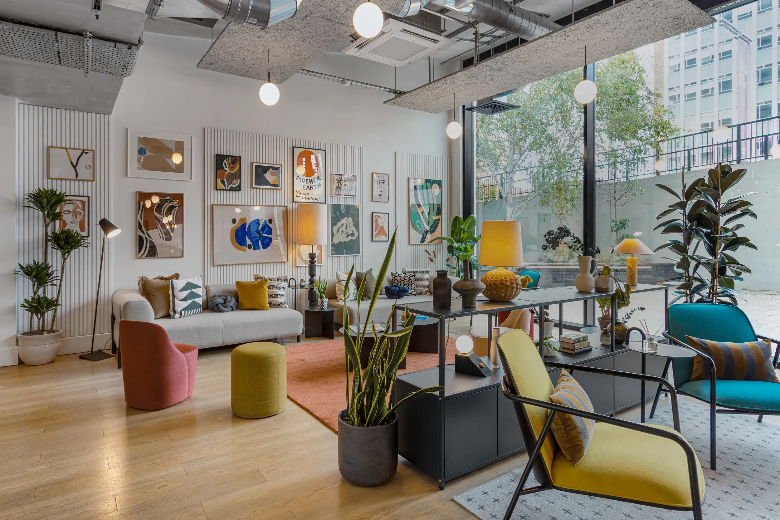 Residents' lounge at Vonder Wembley, with sofas, plants and a gallery wall beside floor-to-ceiling windows