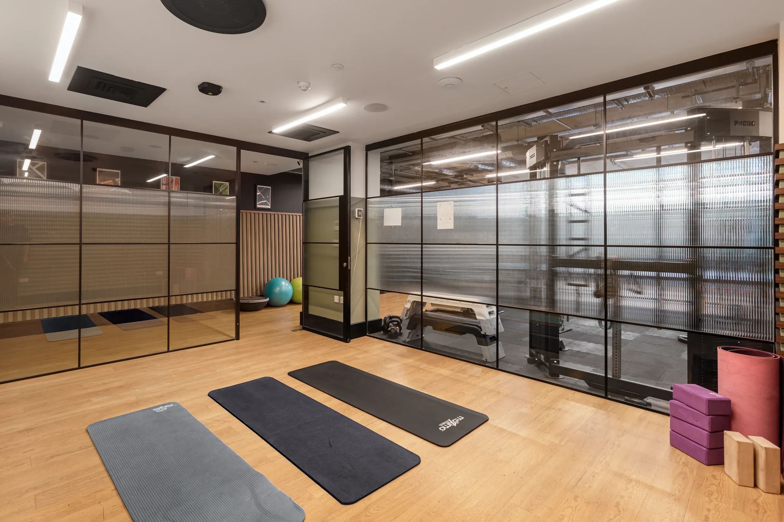 Yoga studio at Vonder Wembley, with mats and blocks on a wooden floor behind glazed partitions