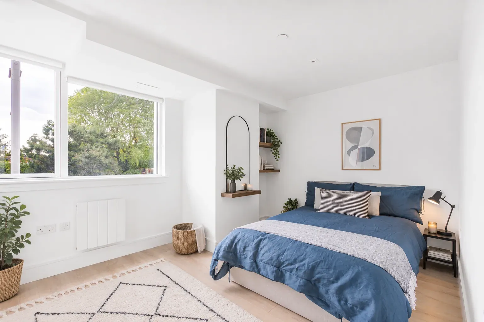 Double bedroom with blue bedding and a window overlooking trees, in a one-bedroom flat at Vonder Wembley